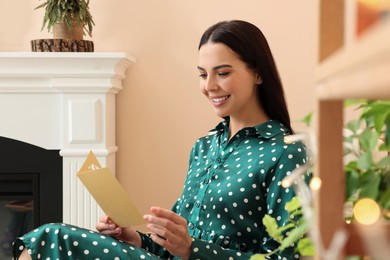 Happy woman reading Christmas greeting card in living room