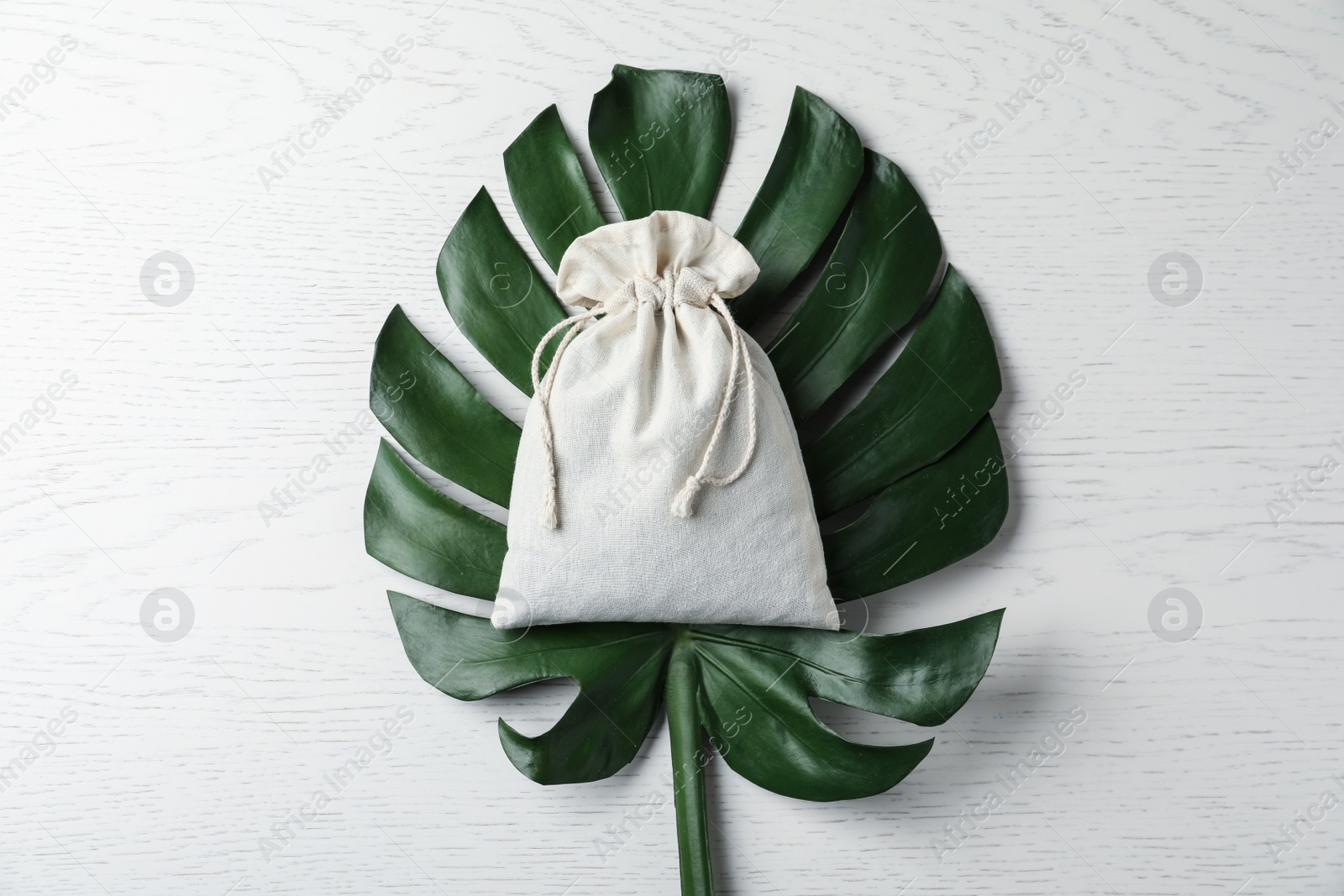 Photo of Cotton eco bag  and monstera leaf on white wooden table, top view