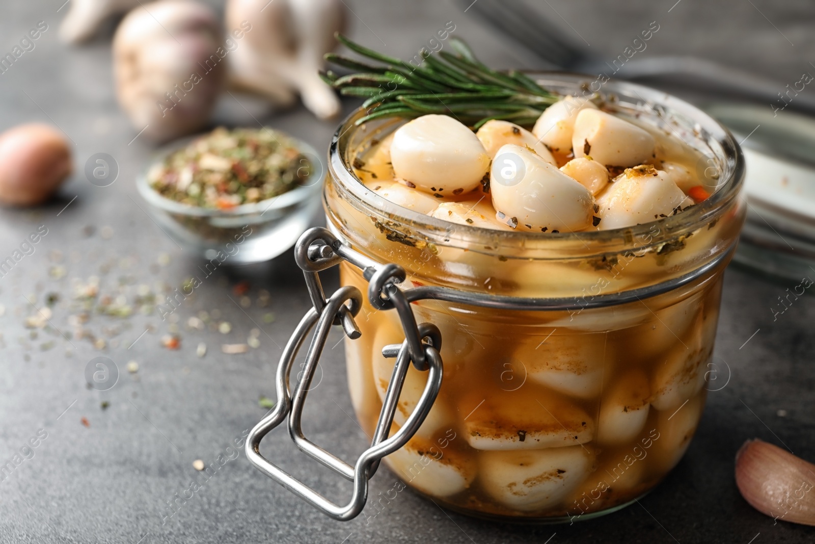 Photo of Preserved garlic in glass jar on table, closeup