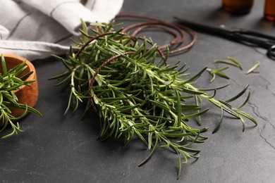 Photo of Sprigs of fresh rosemary with twine on black table, closeup