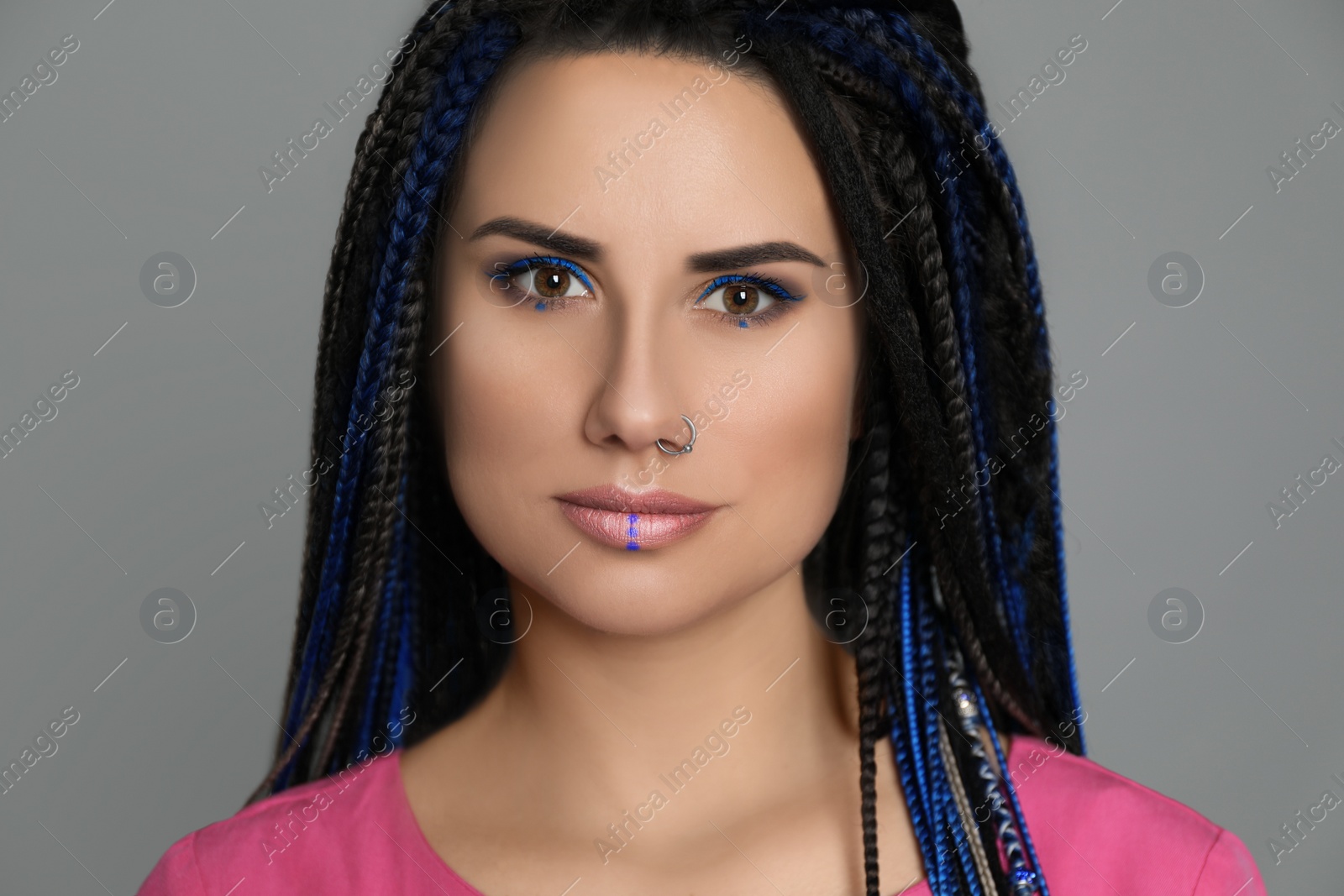 Photo of Beautiful young woman with nose piercing and dreadlocks on grey background