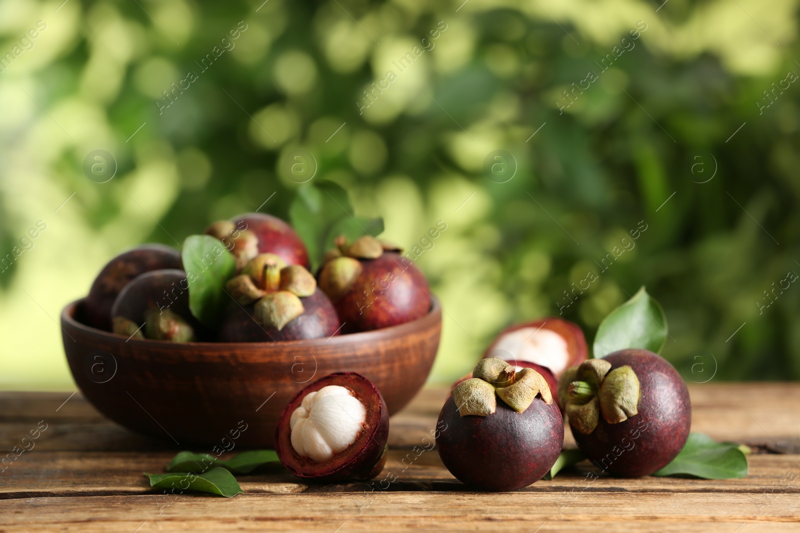 Photo of Delicious tropical mangosteen fruits on wooden table