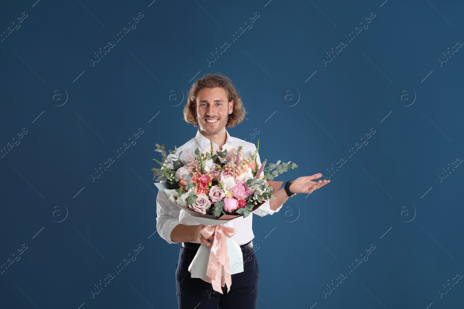 Photo of Young handsome man with beautiful flower bouquet on blue background