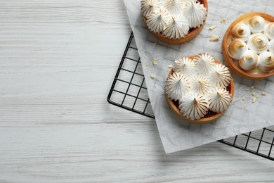 Tartlets with meringue on white wooden table, top view and space for text. Delicious dessert