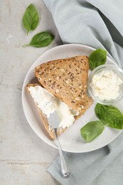 Photo of Pieces of bread with cream cheese and basil leaves on light gray table, top view