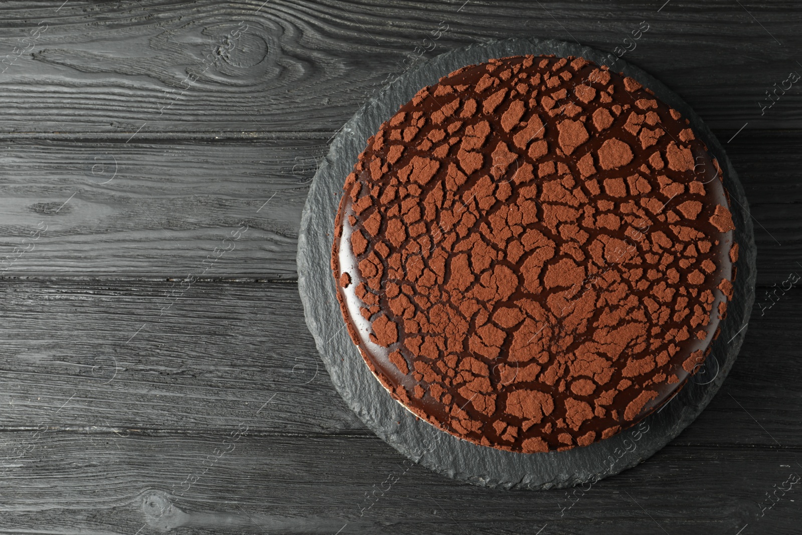 Photo of Delicious chocolate truffle cake on black wooden table, top view. Space for text