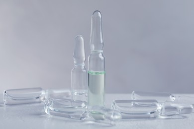 Photo of Pharmaceutical ampoules with medication on white table against light background