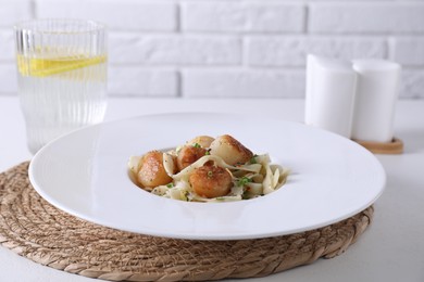 Photo of Delicious scallop pasta with spices in bowl on white table