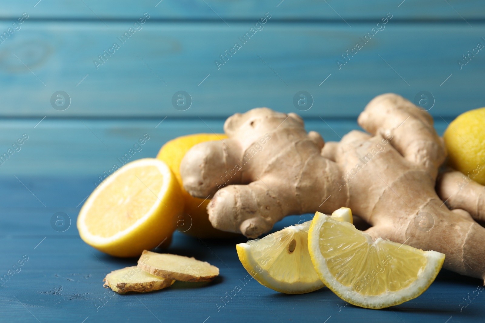 Photo of Fresh lemons and ginger on blue wooden table, closeup