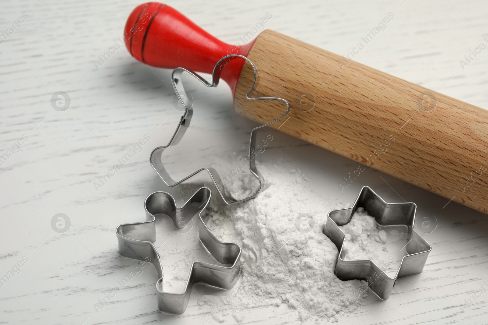 Photo of Cookie cutters, rolling pin and flour on white wooden table