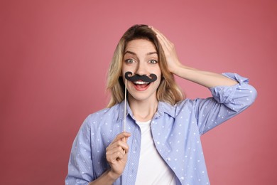 Photo of Funny woman with fake mustache on dusty rose background