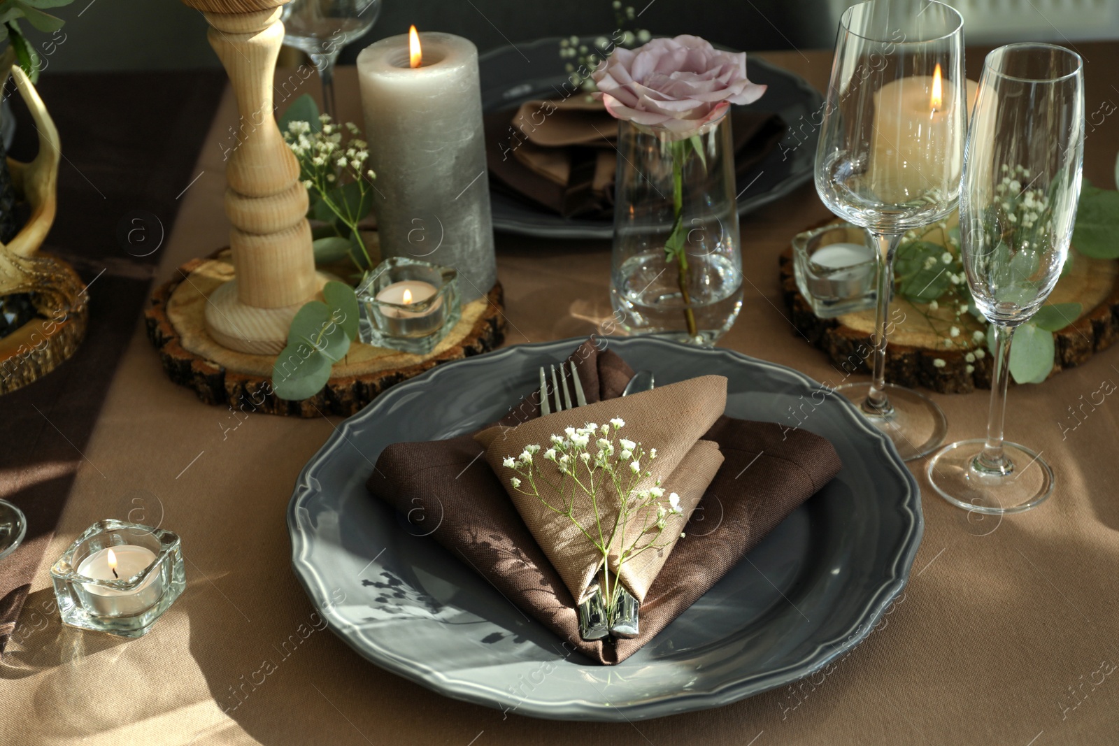 Photo of Festive table setting with beautiful tableware, candles and floral decor