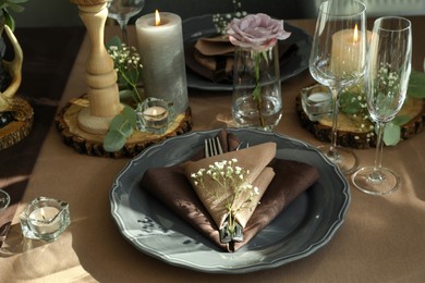 Photo of Festive table setting with beautiful tableware, candles and floral decor