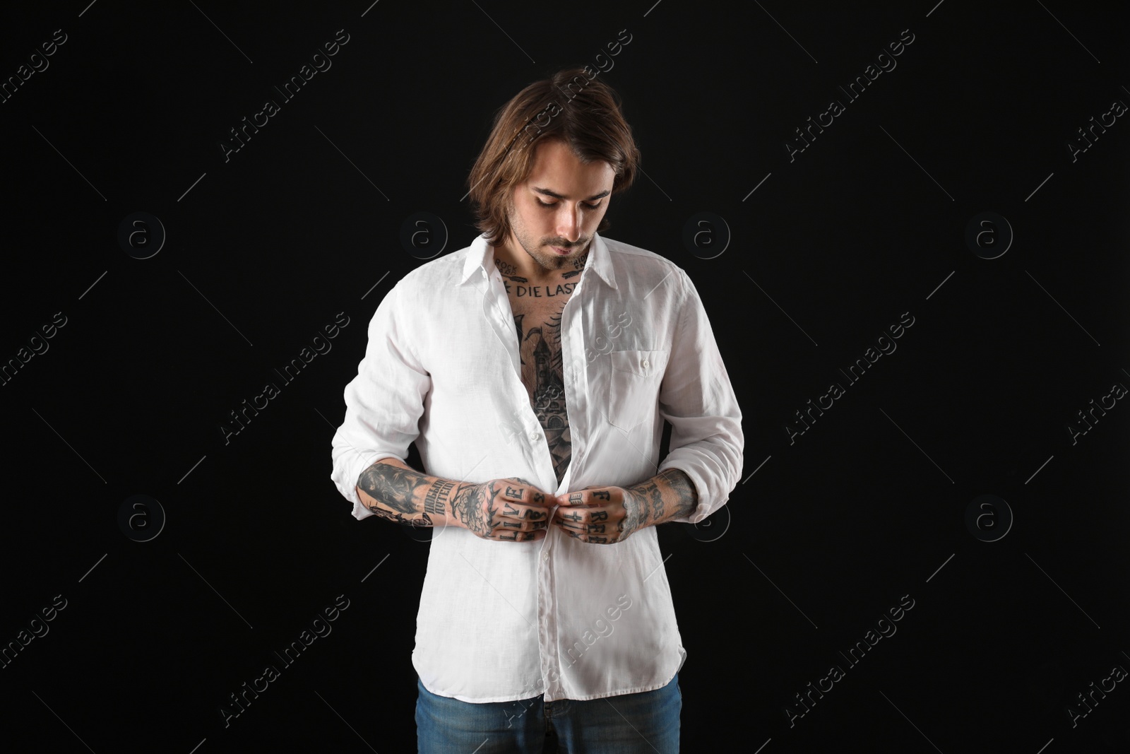 Photo of Young man with tattoos on body against black background