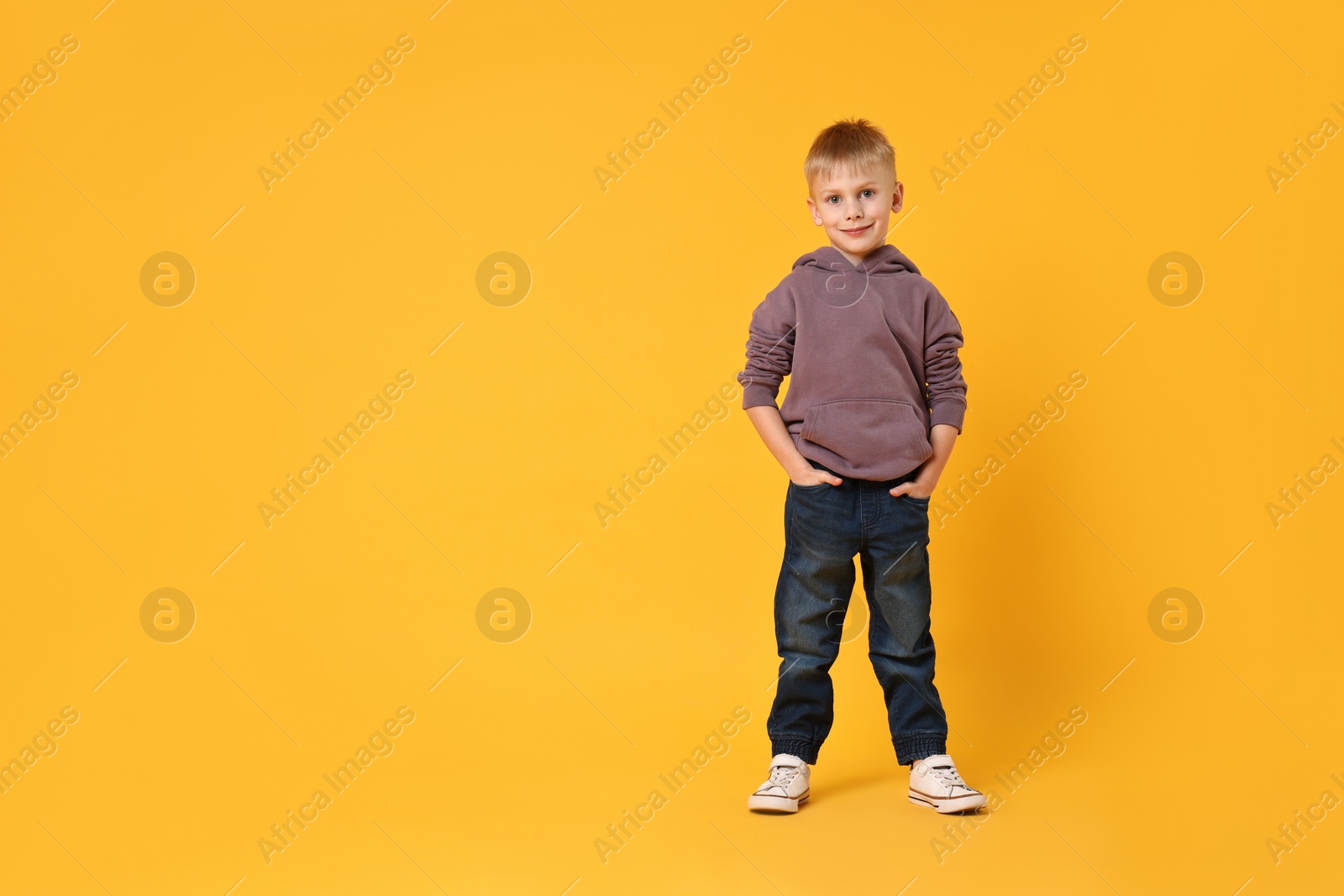 Photo of Happy little boy dancing on yellow background. Space for text