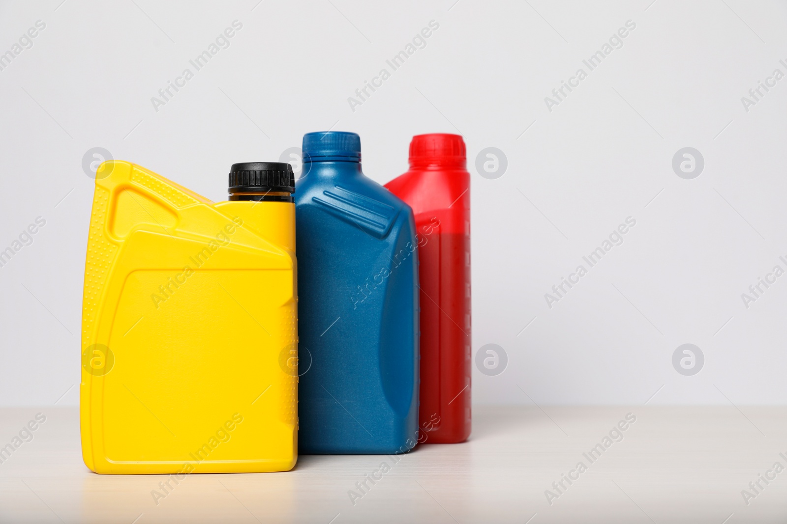 Photo of Motor oil in different canisters on table against white background, space for text