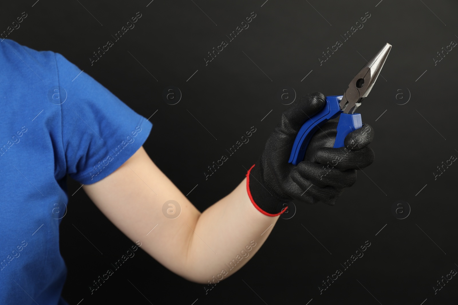 Photo of Woman with needle nose pliers on dark background, closeup