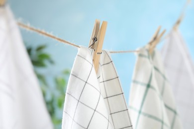 Photo of Washing line with wooden clothespins and fabrics against blurred background