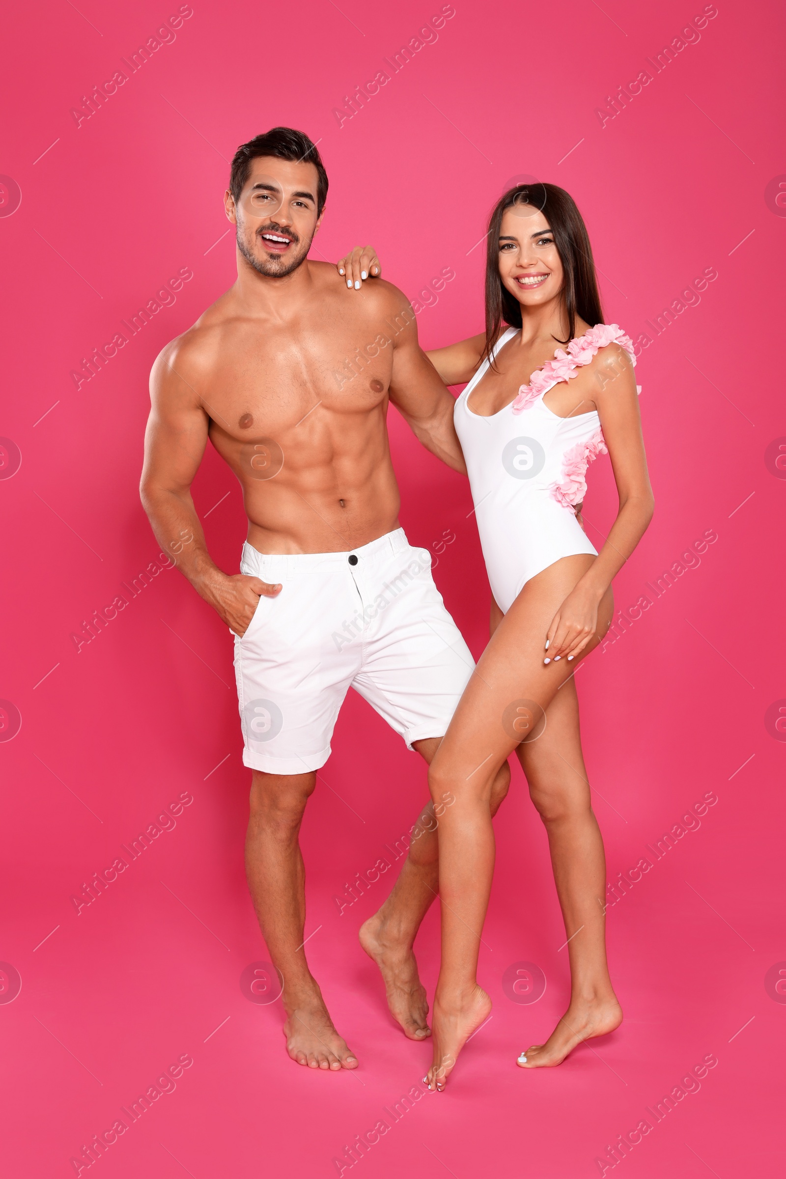 Photo of Young attractive couple in beachwear on pink background