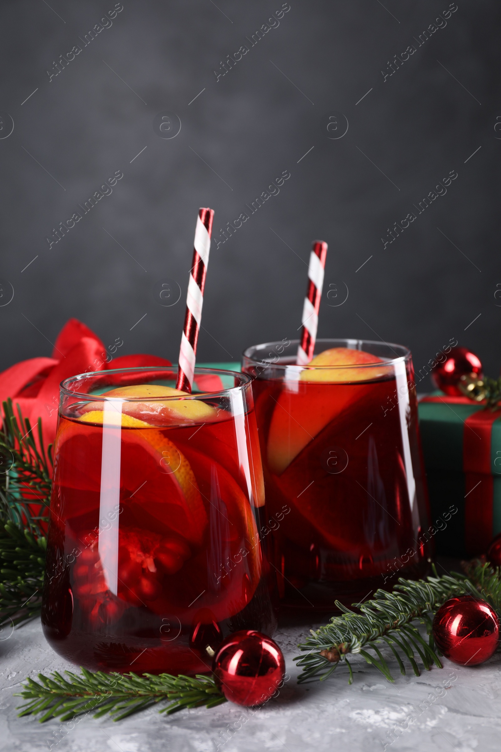 Photo of Delicious Sangria drink in glasses and Christmas decorations on grey table, closeup