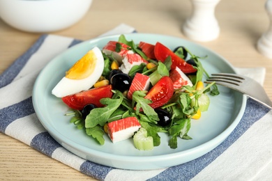 Tasty crab stick salad served on wooden table, closeup