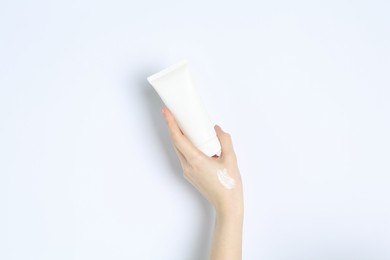 Woman with tube of cream on white background, closeup