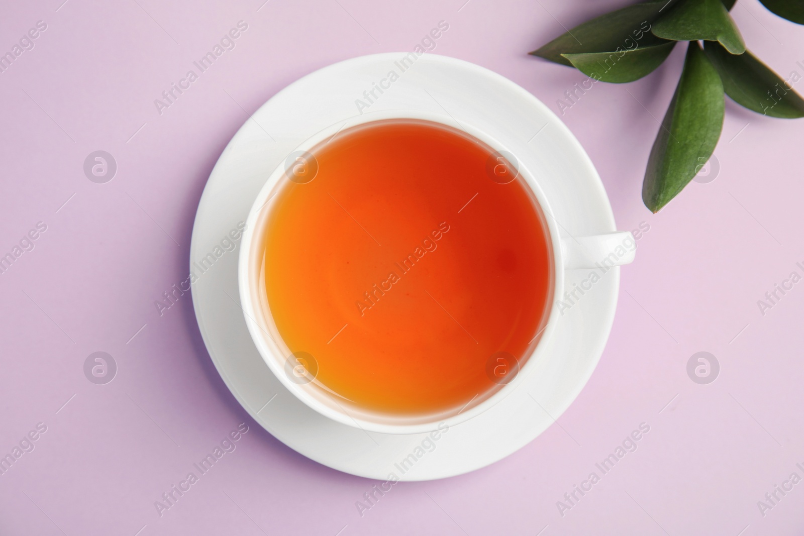 Photo of Cup of delicious tea with green leaves on color background, top view