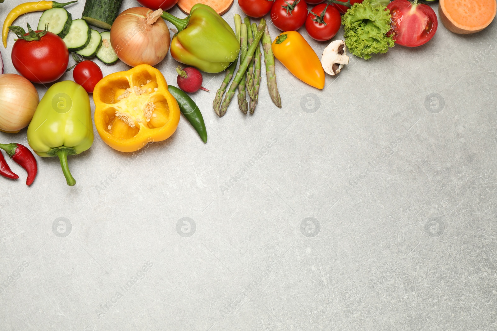 Photo of Flat lay composition with fresh vegetables on grey table. Space for text