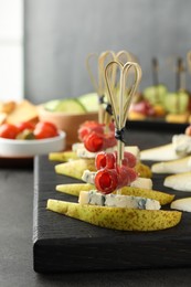 Tasty canapes with pears, blue cheese and prosciutto on grey table, closeup