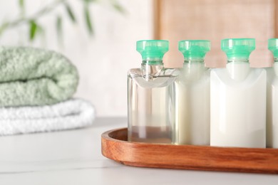 Photo of Mini bottles of cosmetic products on white table against blurred background. Space for text