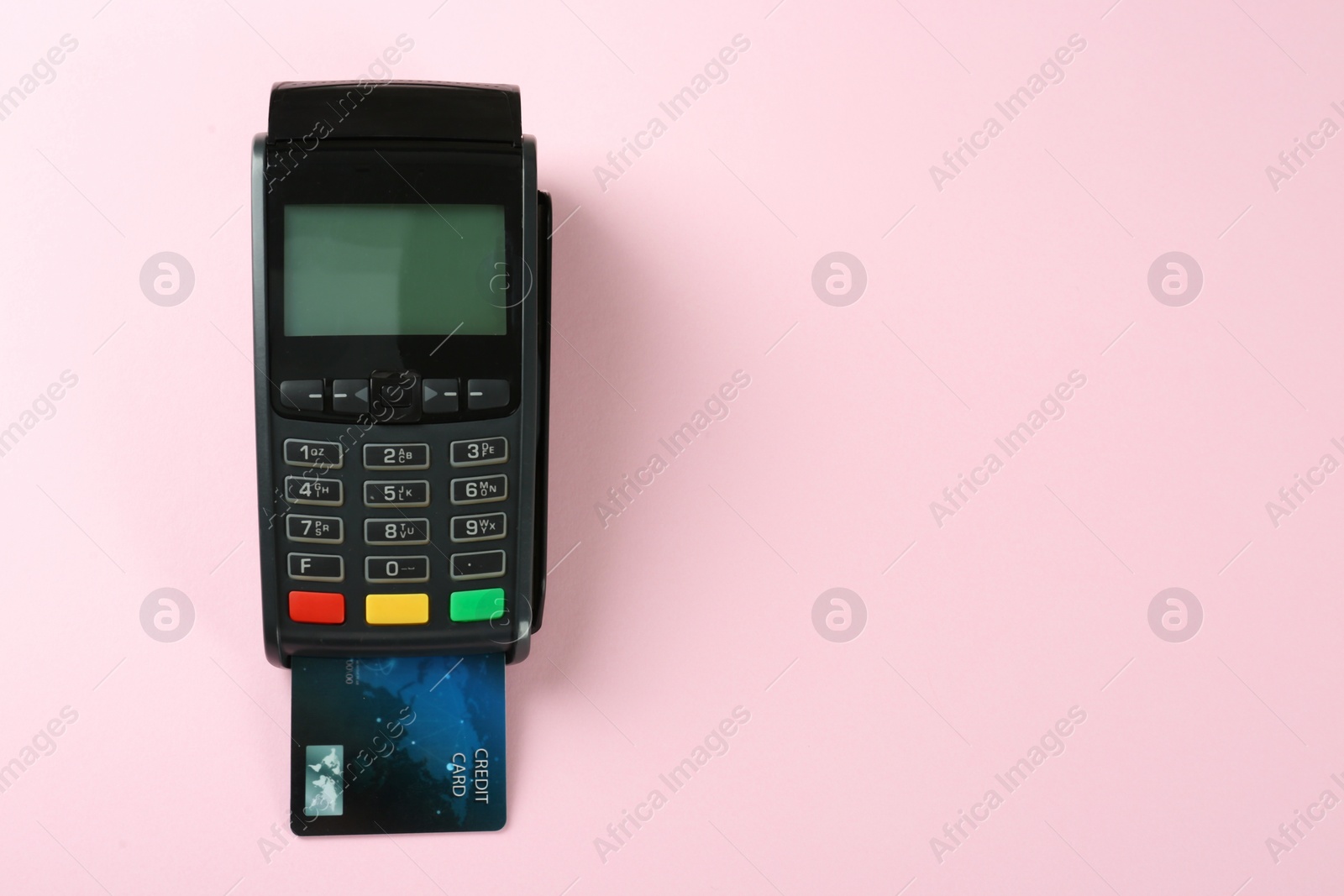 Photo of New modern payment terminal with credit card on pink background, top view. Space for text