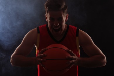 Basketball player with ball on black background