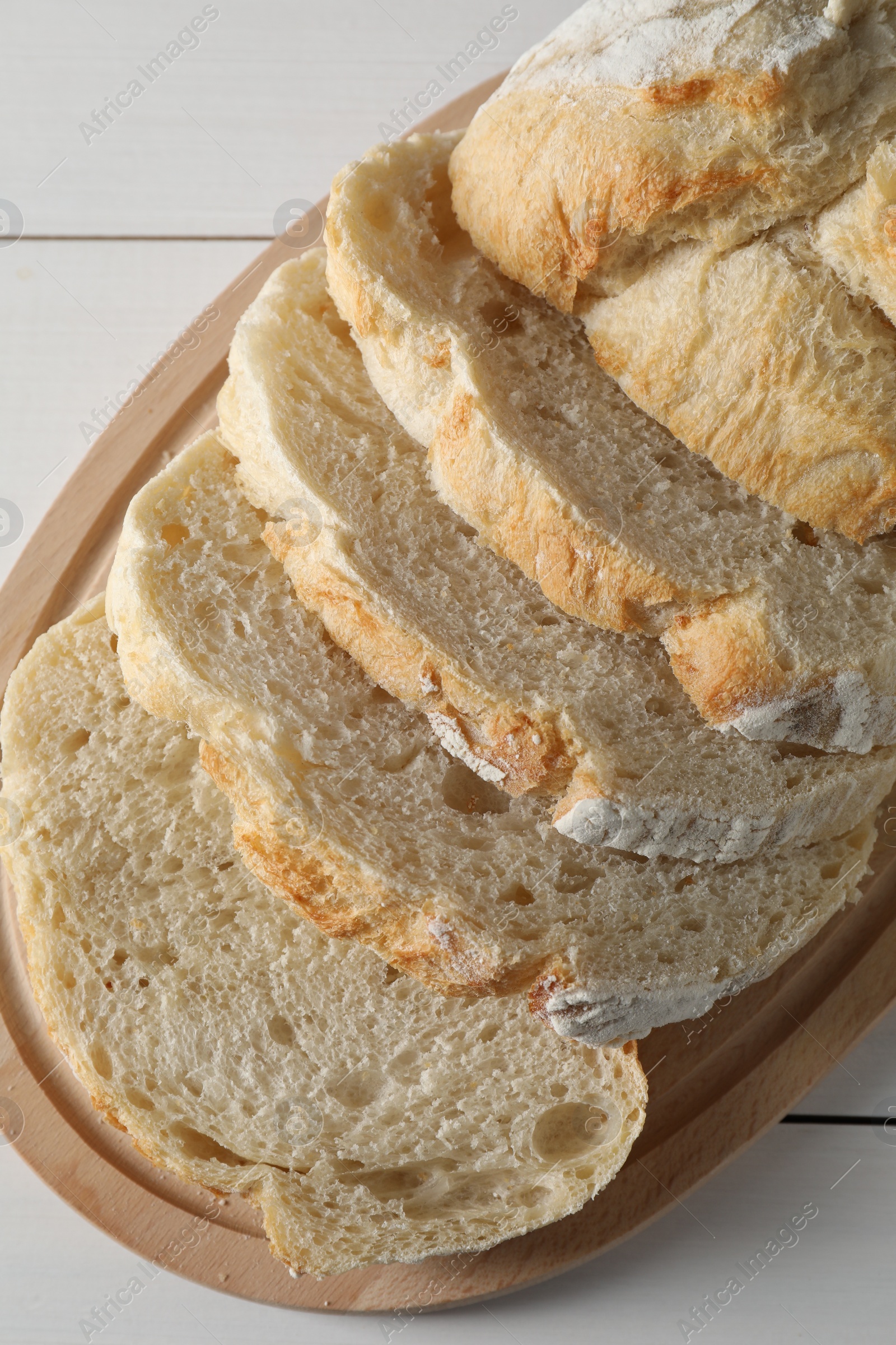 Photo of Freshly baked cut sourdough bread on white wooden table, top view