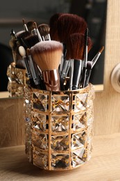 Set of professional makeup brushes near mirror on wooden table