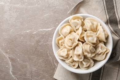 Photo of Tasty dumplings in bowl on marble table, flat lay. Space for text