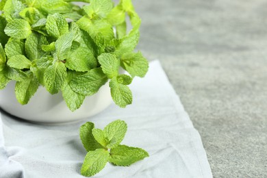 Photo of Bowl with fresh green mint leaves on grey table, closeup. Space for text