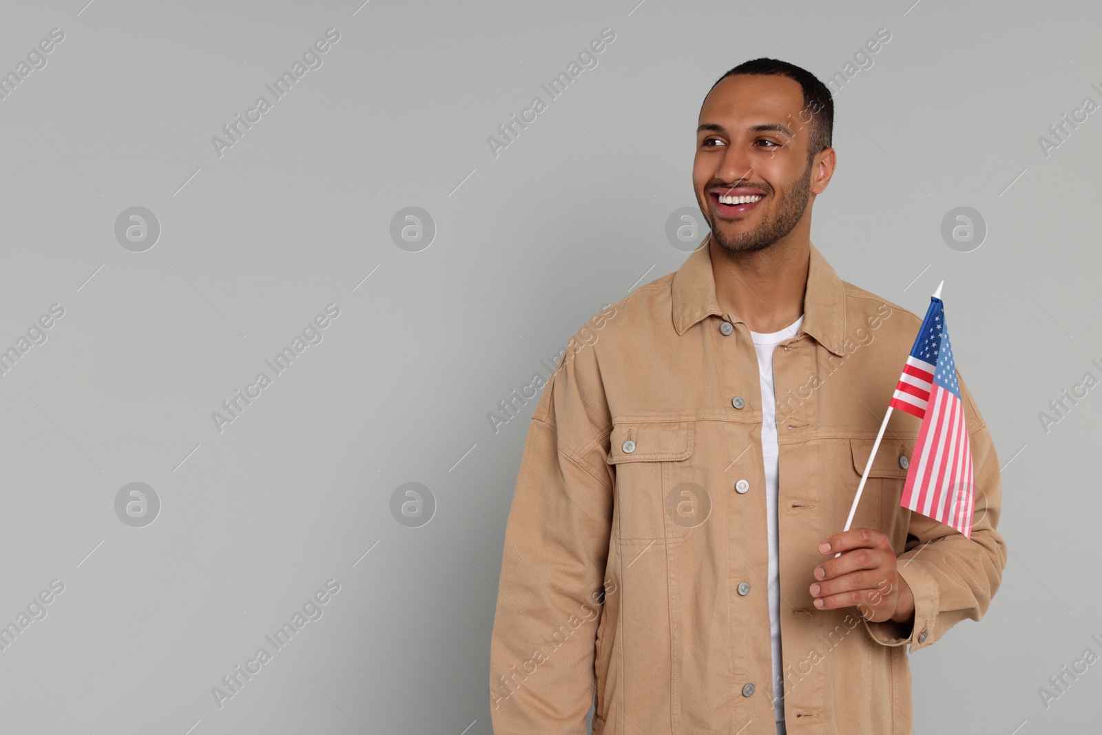 Photo of 4th of July - Independence Day of USA. Happy man with American flag on light grey background, space for text