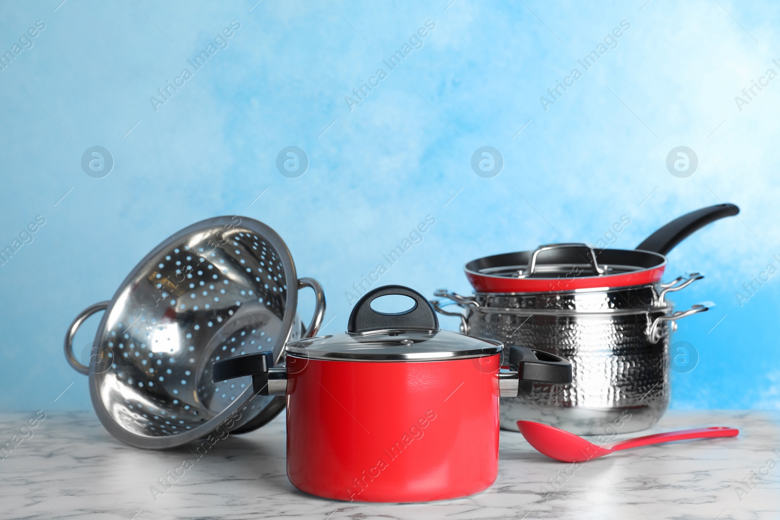 Photo of Set of clean cookware on table against color background. Space for text