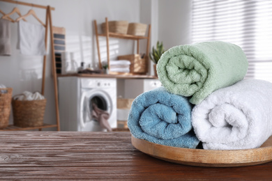 Image of Tray with clean soft towels on wooden table in bathroom. Space for text