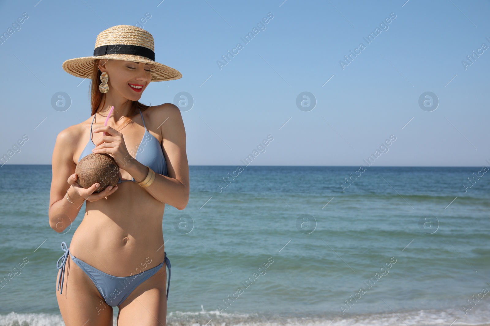 Photo of Attractive woman in bikini holding exotic cocktail near sea