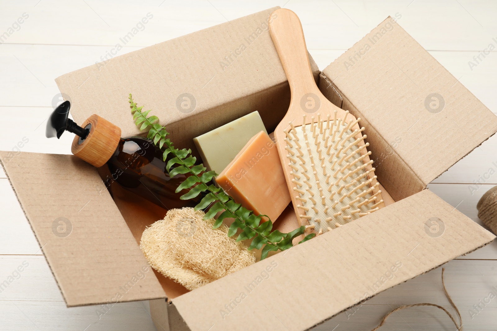 Photo of Cardboard box with eco friendly products on white wooden table, closeup