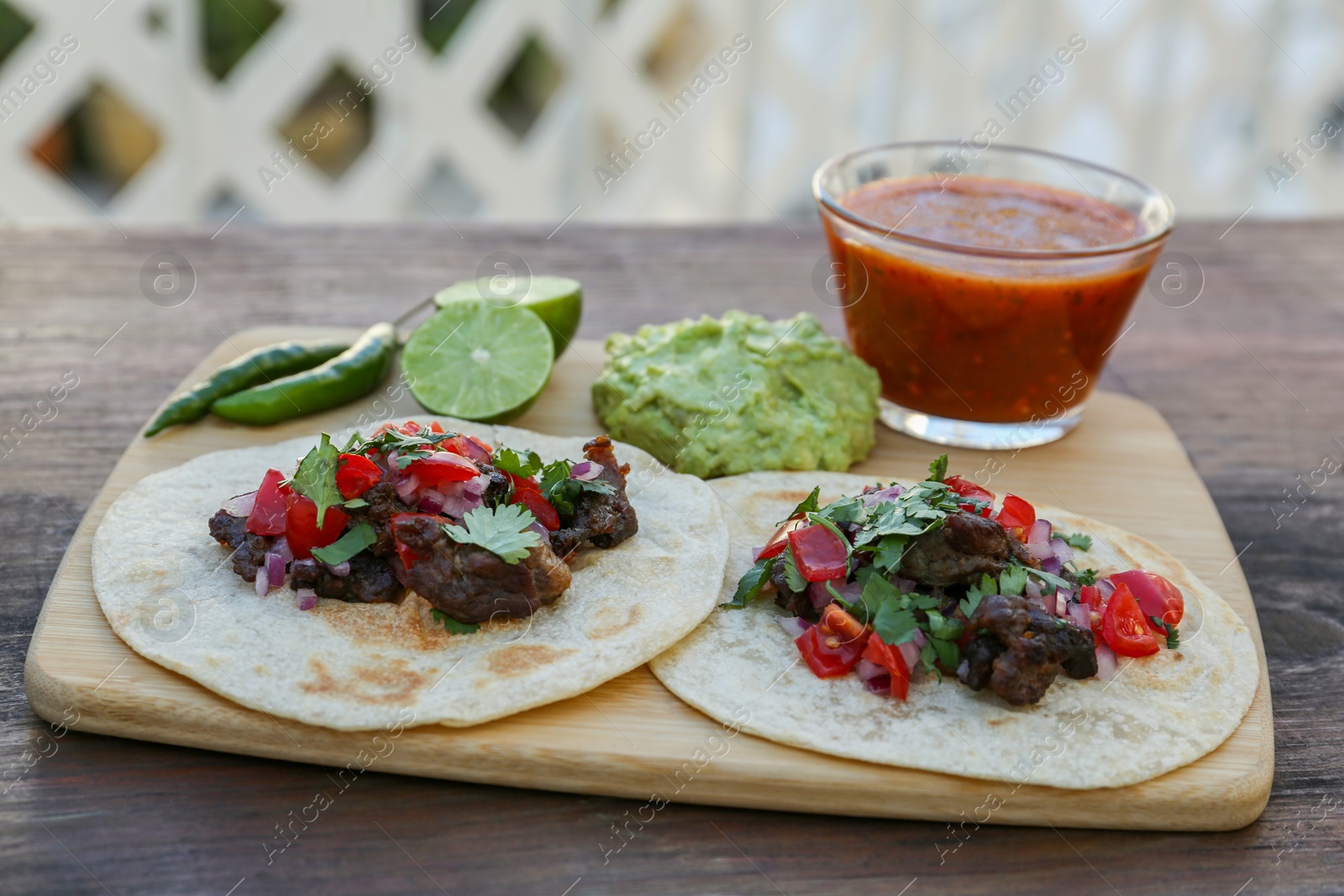 Photo of Delicious tacos and ingredients on wooden table. Mexican food