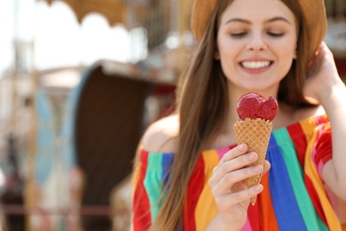Young happy woman with ice cream cone in amusement park. Space for text