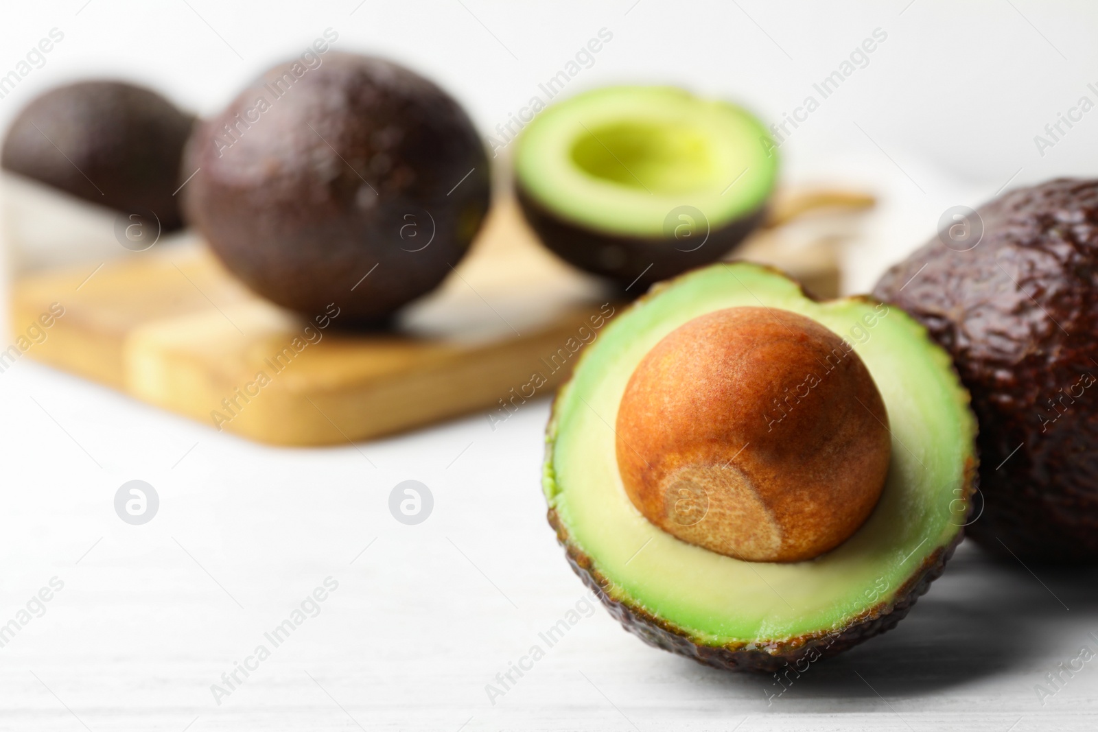 Photo of Delicious ripe avocados on white wooden table