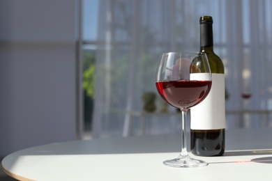 Photo of Glass and bottle with delicious wine on table indoors