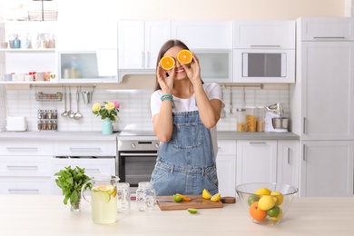Photo of Young woman preparing lemonade on table in kitchen. Natural detox drink
