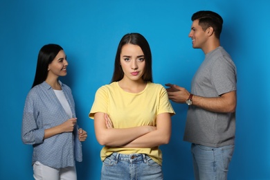 Unhappy woman feeling jealous while couple spending time together on blue background