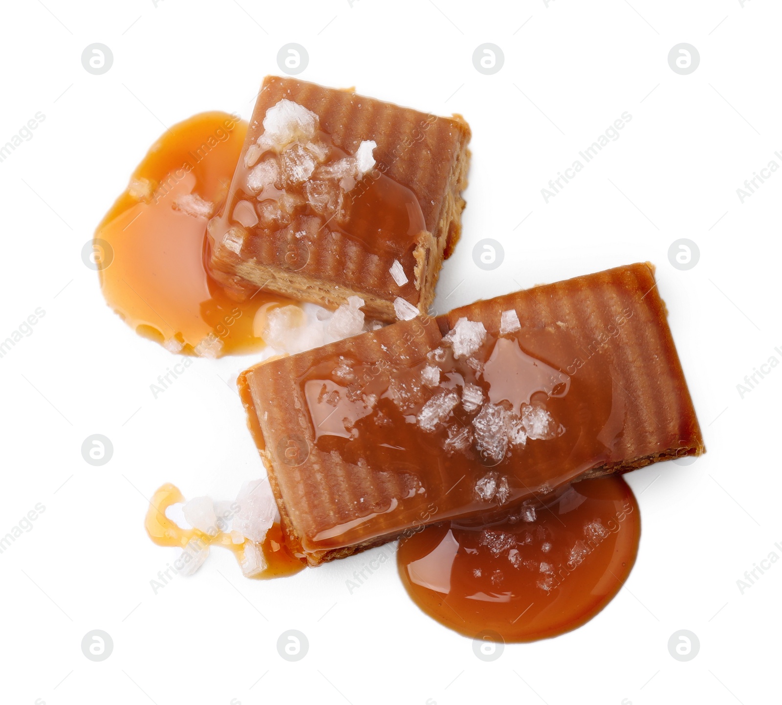 Photo of Yummy caramel candies and sea salt isolated on white, top view