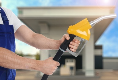 Worker holding fuel nozzle near gas station, closeup