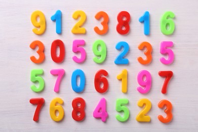 Colorful numbers on white wooden school desk, flat lay